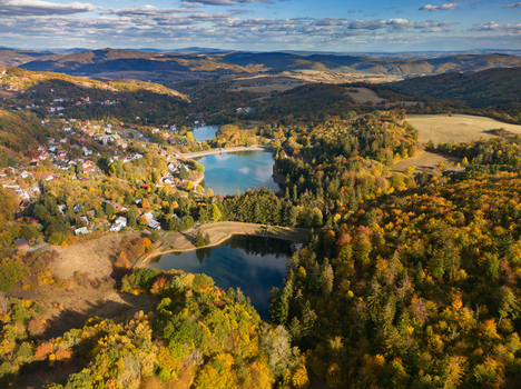 Aerial view of Velka Vindsachta Evickino and Pachomia lakes surrounded by vibrant autumn forests and the town of Stiavnicke Bane Banskobystricky kraj Slovakia.
