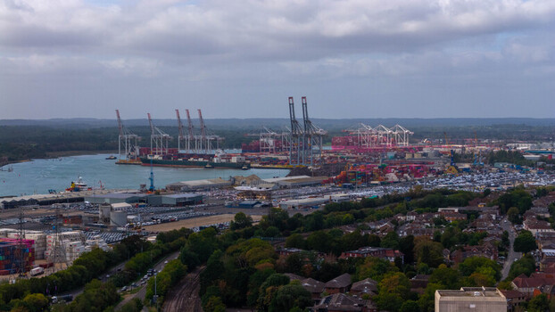 Aerial view of the busy Port of Southampton featuring large container ships towering cranes and extensive rows of parked vehicles along the waterfront in Southampton England United Kingdom. Aerial view of the busy Port of Southampton featuring large container ships towering cranes and extensive rows of parked vehicles along the waterfront in Southampton England United Kingdom.