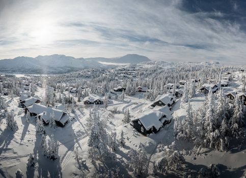 Aerial view of Gaustablikk Fjellresort featuring snow covered wooden cabins nestled among frost laden pine trees in a mountainous winter landscape in Rjukan Telemark Norway. Aerial view of Gaustablikk Fjellresort featuring snow covered wooden cabins nestled among frost laden pine trees in a mountainous winter landscape in Rjukan Telemark Norway.