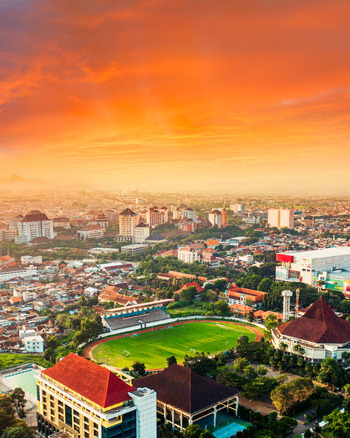 Aerial view of Cakrawala Stadium surrounded by urban buildings and lush greenery under a vibrant sunset sky in Kecamatan Lowokwaru Jawa Timur Indonesia. Aerial view of Cakrawala Stadium surrounded by urban buildings and lush greenery under a vibrant sunset sky in Kecamatan Lowokwaru Jawa Timur Indonesia.