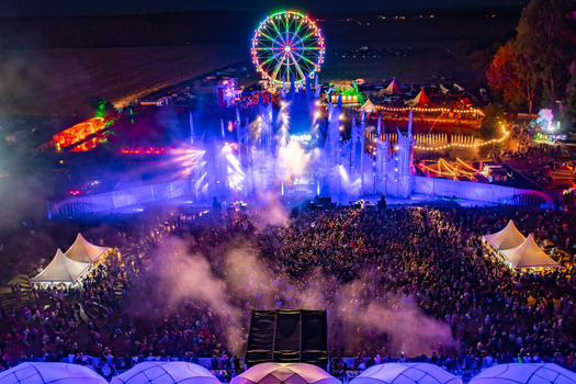 Herzogenaurach Germany 22 July 2022 Aerial view of Open Beatz Festival with a large crowd illuminated stage and a colorful Ferris wheel at night. Herzogenaurach Germany 22 July 2022 Aerial view of Open Beatz Festival with a large crowd illuminated stage and a colorful Ferris wheel at night.