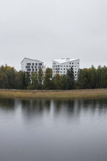 View of modern white apartment buildings with angular roofs nestled among autumn colored trees along the shore of a calm lake in Jyvaskyla Central Finland Finland.