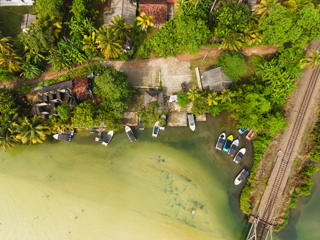 Aerial view of small boats moored along the tropical shoreline of Koggala Lake with lush palm trees and a railway track near Koggala Southern Province Sri Lanka. Aerial view of small boats moored along the tropical shoreline of Koggala Lake with lush palm trees and a railway track near Koggala Southern Province Sri Lanka.