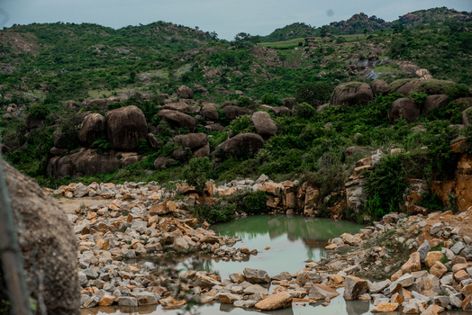 View of a rocky landscape with large boulders a small pond and green vegetation nestled among hills in Jos North Plateau Nigeria. View of a rocky landscape with large boulders a small pond and green vegetation nestled among hills in Jos North Plateau Nigeria.