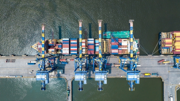 Aerial view of Jawaharlal Nehru Port Authority terminal with a container ship being loaded by cranes and colorful shipping containers in Juna Sheva Maharashtra India. Aerial view of Jawaharlal Nehru Port Authority terminal with a container ship being loaded by cranes and colorful shipping containers in Juna Sheva Maharashtra India.