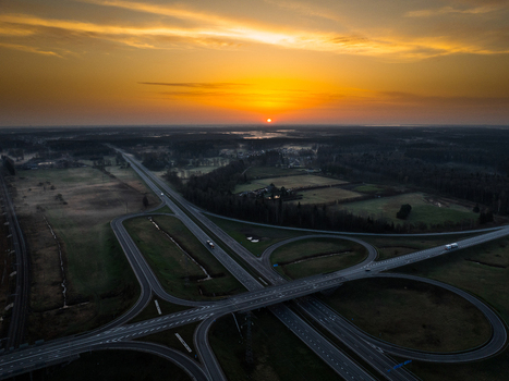Aerial view of the A5 and A8 highway interchange at sunset with golden light over the surrounding fields and forests in Olaine parish Olaine Municipality Latvia. Aerial view of the A5 and A8 highway interchange at sunset with golden light over the surrounding fields and forests in Olaine parish Olaine Municipality Latvia.