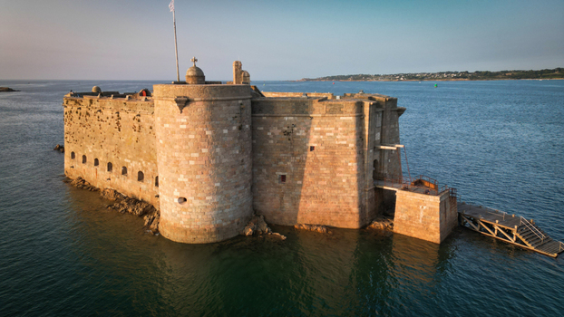 Aerial view of the imposing Ch&acirc;teau du Taureau fortress stands defiant against the teal sea its ancient stones warmed by the sun s golden embrace Plouezoc h Bretagne France.