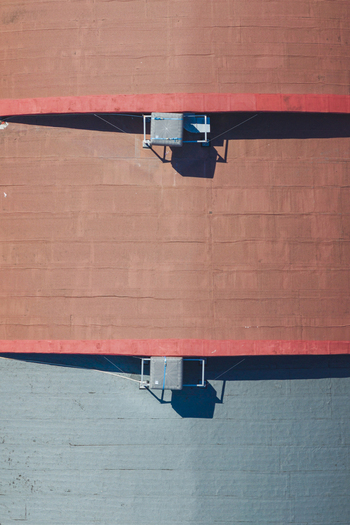Aerial view of a flat roof with red and grey sections and ventilation units casting shadows in Arezzo Tuscany Italy. Aerial view of a flat roof with red and grey sections and ventilation units casting shadows in Arezzo Tuscany Italy.