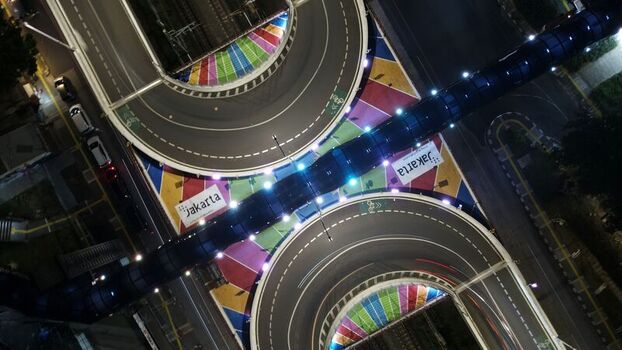 Aerial view of Flyover Tapal Kuda Jakarta at night featuring colorful road markings and illuminated pedestrian bridge in Pasar Minggu Daerah Khusus Ibukota Indonesia. Aerial view of Flyover Tapal Kuda Jakarta at night featuring colorful road markings and illuminated pedestrian bridge in Pasar Minggu Daerah Khusus Ibukota Indonesia.