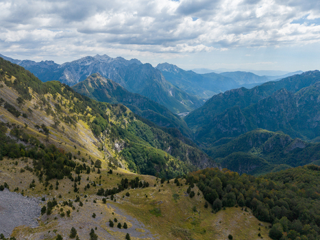 Aerial view of the Albanian Alps with rugged mountain peaks lush green slopes and rocky terrain under a cloudy sky in Shkoder Shkoder County Albania. Aerial view of the Albanian Alps with rugged mountain peaks lush green slopes and rocky terrain under a cloudy sky in Shkoder Shkoder County Albania.