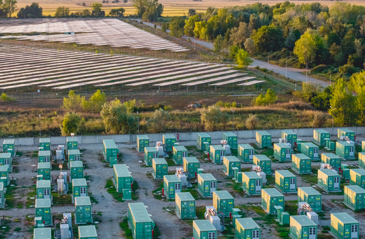 Aerial view of battery energy storage systems beside a large solar photovoltaic installation at an industrial power site in Trino Piedmont Italy.