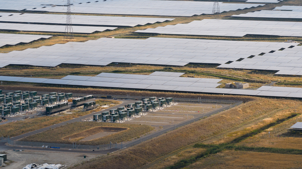 Aerial view of a large scale solar farm with rows of photovoltaic panels and battery energy storage containers in London England United Kingdom.
