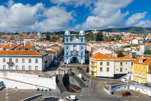 Aerial view of the blue Igreja da Misericordia church and historic white buildings with orange rooftops under a cloudy sky in Angra do Heroismo Azores Portugal.