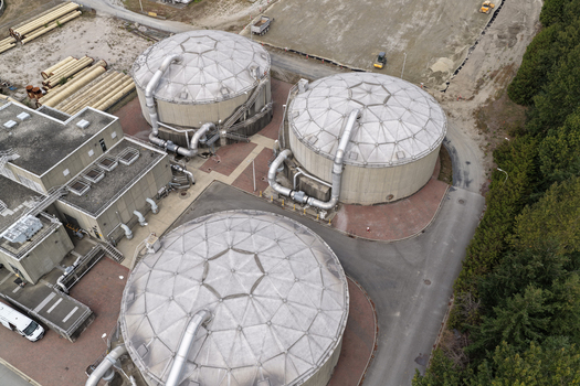 Aerial view of Richmond Wastewater Treatment Plant featuring large circular digester tanks industrial piping and surrounding paved areas in Richmond British Columbia Canada. Aerial view of Richmond Wastewater Treatment Plant featuring large circular digester tanks industrial piping and surrounding paved areas in Richmond British Columbia Canada.