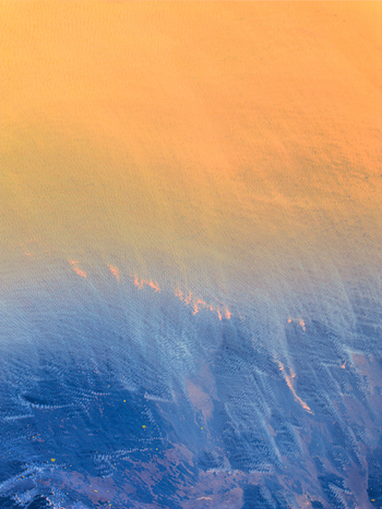 Aerial view of the rugged Icelandic landscape featuring a dramatic transition from golden sunset light to deep blue shadows across volcanic terrain in Iceland. Aerial view of the rugged Icelandic landscape featuring a dramatic transition from golden sunset light to deep blue shadows across volcanic terrain in Iceland.