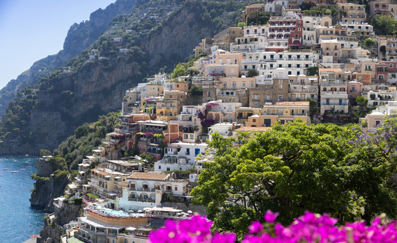 Aerial view of Positano with its colorful houses cascading down the cliffside towards the Mediterranean Sea surrounded by lush greenery and bright sunlight in Positano Campania Italy. Aerial view of Positano with its colorful houses cascading down the cliffside towards the Mediterranean Sea surrounded by lush greenery and bright sunlight in Positano Campania Italy.