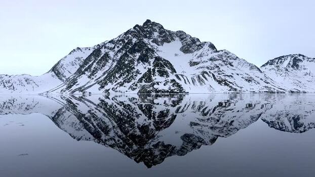 Aerial view of snowy mountain reflection in a fjord Greenland. Aerial view of snowy mountain reflection in a fjord Greenland.