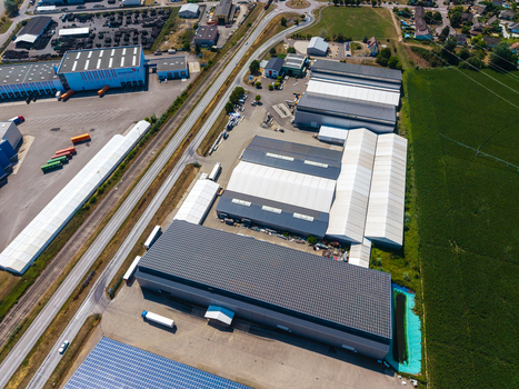 Aerial view of Hombourg Logistic park featuring large industrial warehouses with solar panels adjacent railway tracks and surrounding agricultural fields in Hombourg Grand Est France.