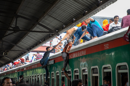 Dhaka Bangladesh 15 June 2018 View of people climbing onto the roof of a Bangladesh Railway train at Airport Railway Station with a child being helped up by passengers. Dhaka Bangladesh 15 June 2018 View of people climbing onto the roof of a Bangladesh Railway train at Airport Railway Station with a child being helped up by passengers.