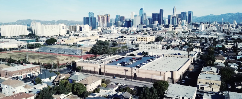 Aerial view of the Los Angeles skyline featuring modern skyscrapers urban sprawl residential rooftops and a large parking lot in the foreground Los Angeles California United States.