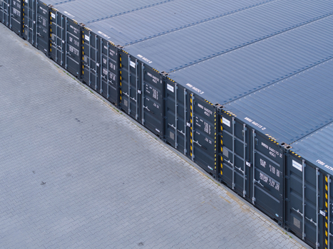 Aerial view of rows of dark blue shipping containers neatly arranged on a paved industrial lot in Poland. Aerial view of rows of dark blue shipping containers neatly arranged on a paved industrial lot in Poland.