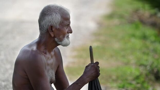 View of an elderly man sitting with an umbrella Bangladesh. View of an elderly man sitting with an umbrella Bangladesh.