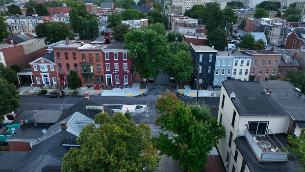 Aerial view of a quiet residential street lined with historic brick row houses lush green trees and parked cars in Harrisburg Pennsylvania United States.