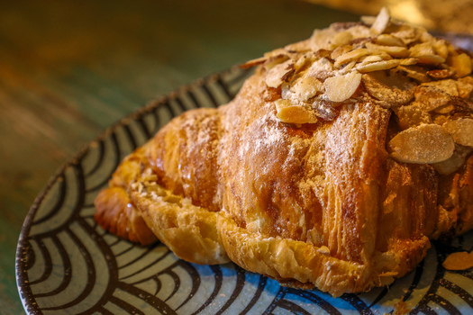 View of an almond croissant topped with sliced almonds and powdered sugar on a decorative plate at Ruba s Bakery Bistro San Jose del Cabo Baja California Sur Mexico.