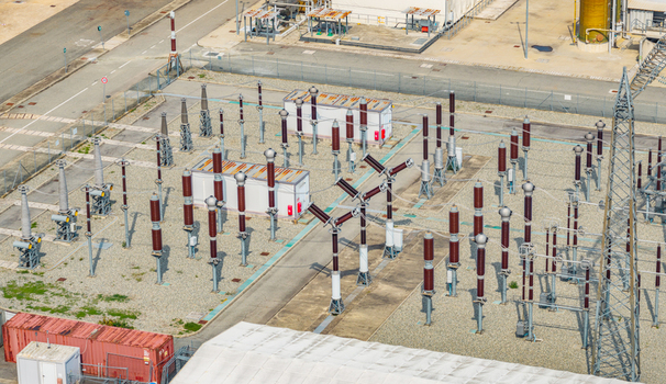 Aerial view of a high voltage electrical substation with circuit breakers insulators and transmission equipment at an industrial power facility in Italy.