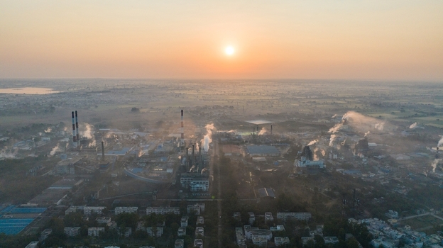 Aerial view of the industrial complex with smoking chimneys and factory buildings under a golden sunrise in Nagda Madhya Pradesh India. Aerial view of the industrial complex with smoking chimneys and factory buildings under a golden sunrise in Nagda Madhya Pradesh India.