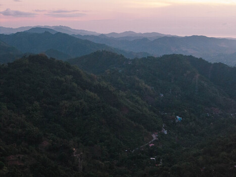 Aerial view of the lush rolling hills of Busay under a soft twilight sky with winding roads nestled in the tropical valley in Cebu City Central Visayas Philippines.