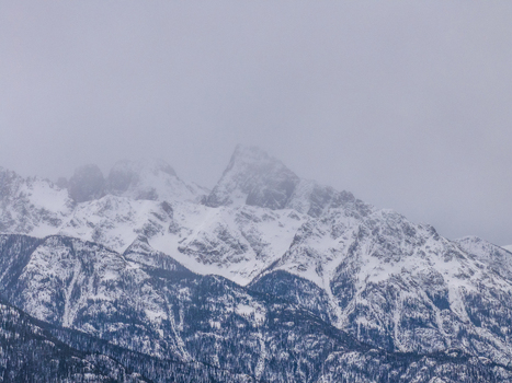 View of snow covered mountain peaks and rugged slopes under a dense overcast sky in Colorado United States.