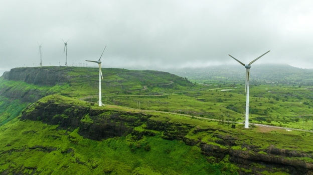 Aerial view of wind turbines standing on lush green hills under a cloudy sky in Igatpuri Maharashtra India. Aerial view of wind turbines standing on lush green hills under a cloudy sky in Igatpuri Maharashtra India.