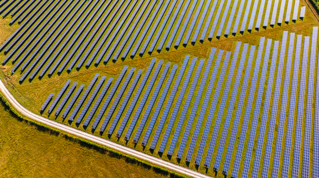 Aerial view of a large solar farm with rows of photovoltaic panels arranged in a field with a dirt path in Dorset England United Kingdom. Aerial view of a large solar farm with rows of photovoltaic panels arranged in a field with a dirt path in Dorset England United Kingdom.