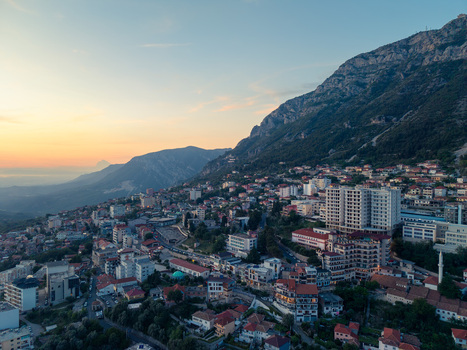 Aerial view of the historic town of Kruje nestled at the foot of a rugged mountain range with red tiled rooftops and modern buildings during sunset Kruje Durres County Albania.