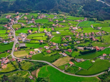 Aerial view of a rural village with houses scattered among lush green fields and winding roads in Cudillero Asturias Spain.
