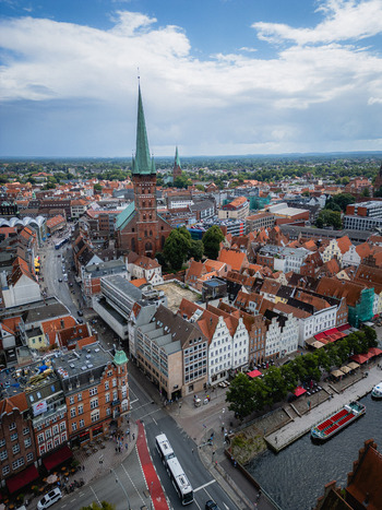 Aerial view of the iconic spire of St. Marien church rises above the terracotta rooftops blending with the Elbe river s shimmering waters L&uuml;beck Schleswig Holstein Germany.