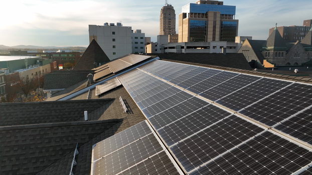Aerial view of solar panels installed on a residential rooftop with urban buildings in the background in Reading Pennsylvania United States. Aerial view of solar panels installed on a residential rooftop with urban buildings in the background in Reading Pennsylvania United States.
