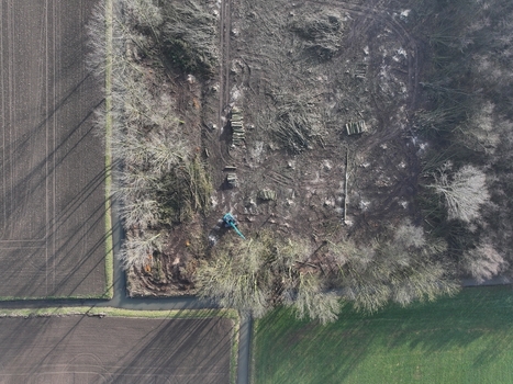 Netherlands 06 July 2026 Aerial view of deforestation activity with a blue excavator piles of logs and cleared land adjacent to agricultural fields. Netherlands 06 July 2026 Aerial view of deforestation activity with a blue excavator piles of logs and cleared land adjacent to agricultural fields.