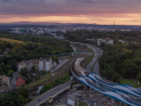 Aerial view of the railway lines and modern pedestrian bridge surrounded by urban buildings and lush greenery in Krakow Lesser Poland Voivode Poland.