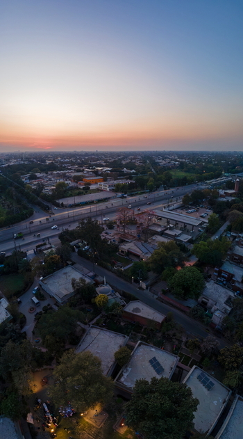 Aerial view of the urban landscape and busy highway at sunset with glowing orange sky and residential rooftops in Lahore Punjab Pakistan. Aerial view of the urban landscape and busy highway at sunset with glowing orange sky and residential rooftops in Lahore Punjab Pakistan.
