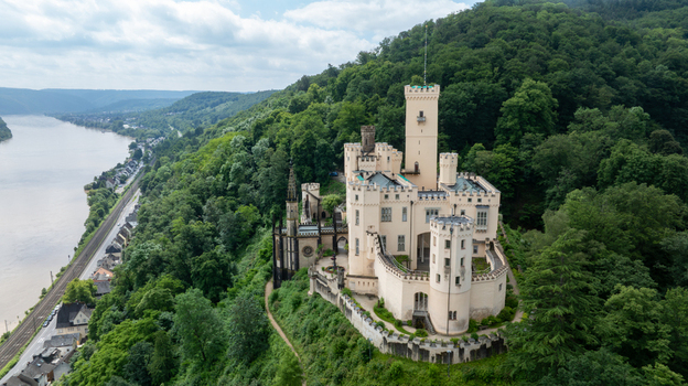 Aerial view of Stolzenfels Castle with Gothic Revival architecture and white towers overlooking the Rhine river valley and lush green forests in Koblenz Rheinland Pfalz Germany. Aerial view of Stolzenfels Castle with Gothic Revival architecture and white towers overlooking the Rhine river valley and lush green forests in Koblenz Rheinland Pfalz Germany.