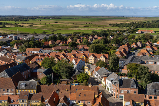 View of the historic red tiled rooftops and surrounding green fields from Ribe Cathedral under a blue sky in Ribe Denmark. View of the historic red tiled rooftops and surrounding green fields from Ribe Cathedral under a blue sky in Ribe Denmark.