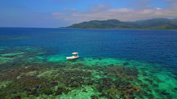 Aerial view of a person in a boat on turquoise water over a reef Honduras. Aerial view of a person in a boat on turquoise water over a reef Honduras.
