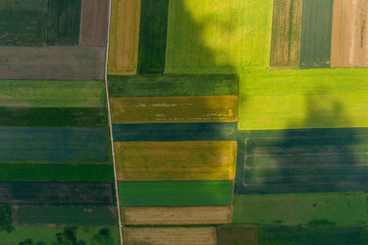 Aerial view of colorful rectangular agricultural fields and a narrow rural path under soft cloud shadows in Forchheim Bavaria Germany. Aerial view of colorful rectangular agricultural fields and a narrow rural path under soft cloud shadows in Forchheim Bavaria Germany.