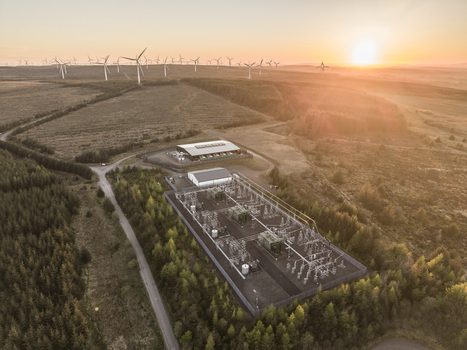 Aerial view of an electrical substation and a vast wind farm on Eaglesham Moor during a golden sunset in Kilmarnock Scotland United Kingdom.