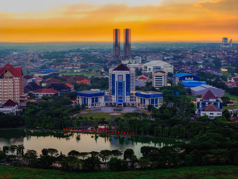 Aerial view of Unesa Lake and the Universitas Negeri Surabaya campus buildings surrounded by greenery and urban landscape under a golden sunset in Kecamatan Lakarsantri Jawa Timur Indonesia. Aerial view of Unesa Lake and the Universitas Negeri Surabaya campus buildings surrounded by greenery and urban landscape under a golden sunset in Kecamatan Lakarsantri Jawa Timur Indonesia.