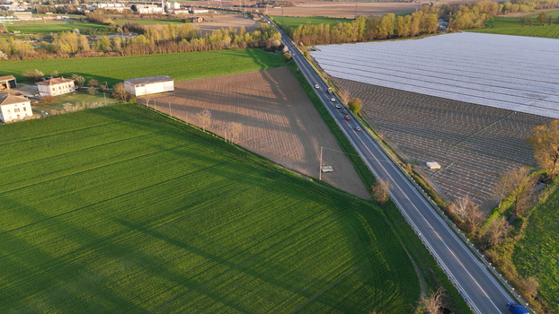 Aerial view of polytunnel fruit growing structures in the Po Valley with green fields a road with cars and agricultural land in Fiorenzuola d Arda Emilia Romagna Italy. Aerial view of polytunnel fruit growing structures in the Po Valley with green fields a road with cars and agricultural land in Fiorenzuola d Arda Emilia Romagna Italy.
