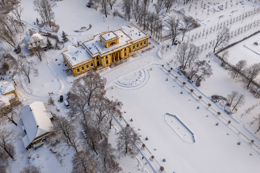 Aerial view of the historic Traku Voke Manor with its yellow neoclassical facade surrounded by a snow covered park and bare winter trees in Vilnius Vilniaus apskritis Lithuania.