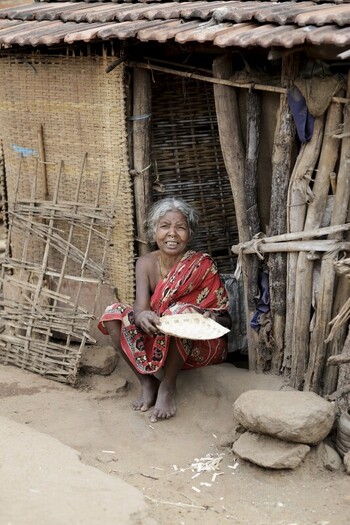 Odisha India 26 March 2026 View of a smiling woman in a red saree squatting by the rustic entrance of a thatched home reflecting a simple life in Odisha. Odisha India 26 March 2026 View of a smiling woman in a red saree squatting by the rustic entrance of a thatched home reflecting a simple life in Odisha.